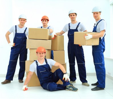 Professional movers carrying furniture through a residential entrance in White City